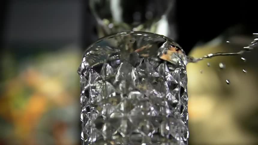 Man pours a cocktail from a jar into a glass and the liquid splashes out of the glass