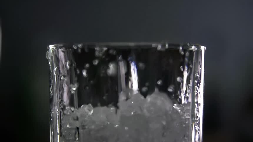 Close up of ice cubes dropping into a glass in studio