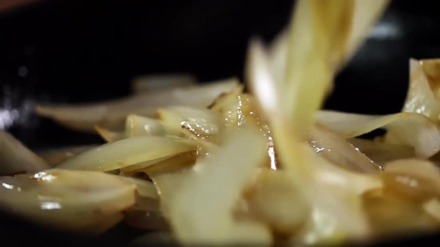 Cooked shallot or onion slices dropping inside a bowl