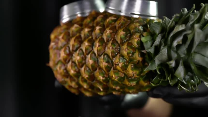 A person places a pineapple used as bowl on top of a stem
