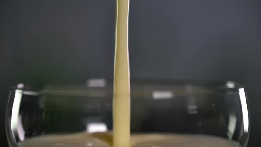 White alcoholic beverage is being poured into a cocktail glass