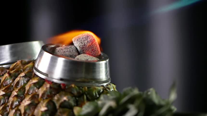 Gas burner ignites flames on charcoal in a stainless ring