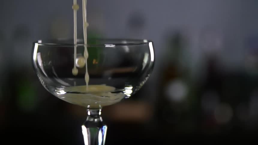 White drink is being poured into a glass