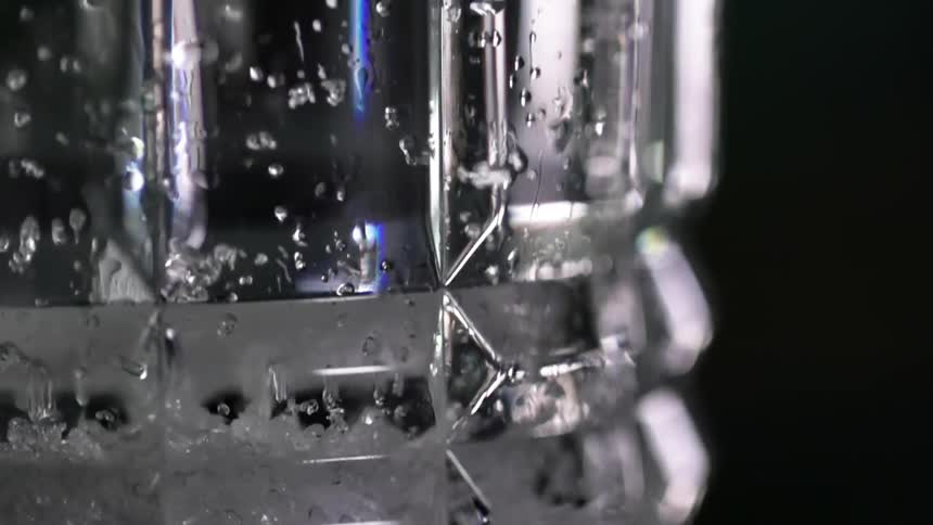 A crystal glass with ice falling in to it