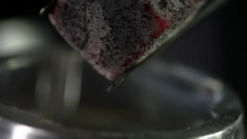 A charcoal cube falls into a metal ash tray