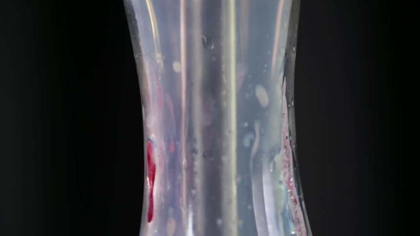 Metal stem sits in the center of a glass vase as bubbles float around it