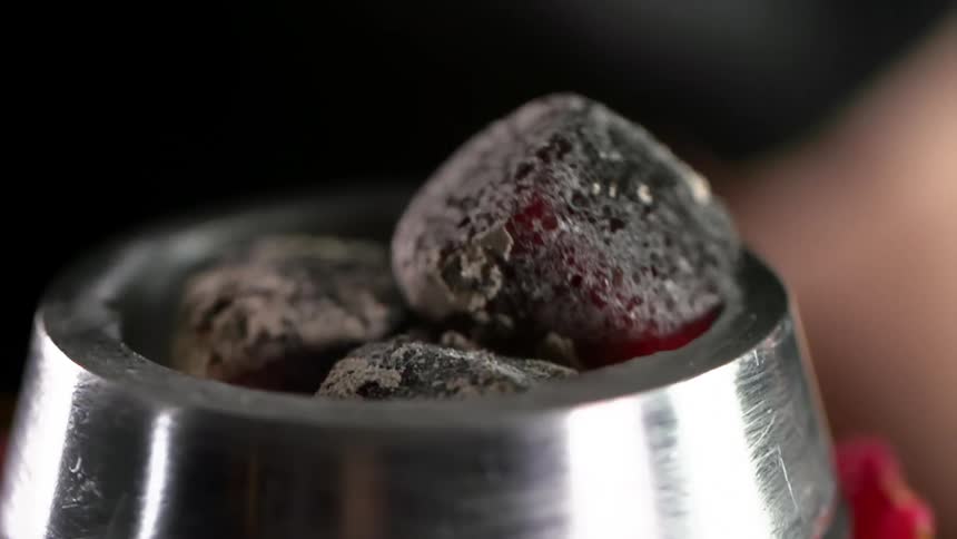 Charcoal being put into a metal bowl