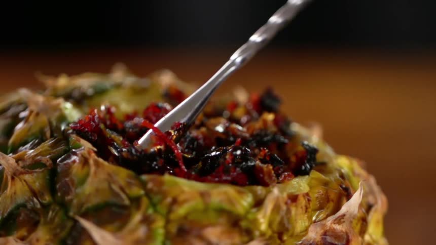 A stainless stirrer pushes tobacco further into a pineapple bowl