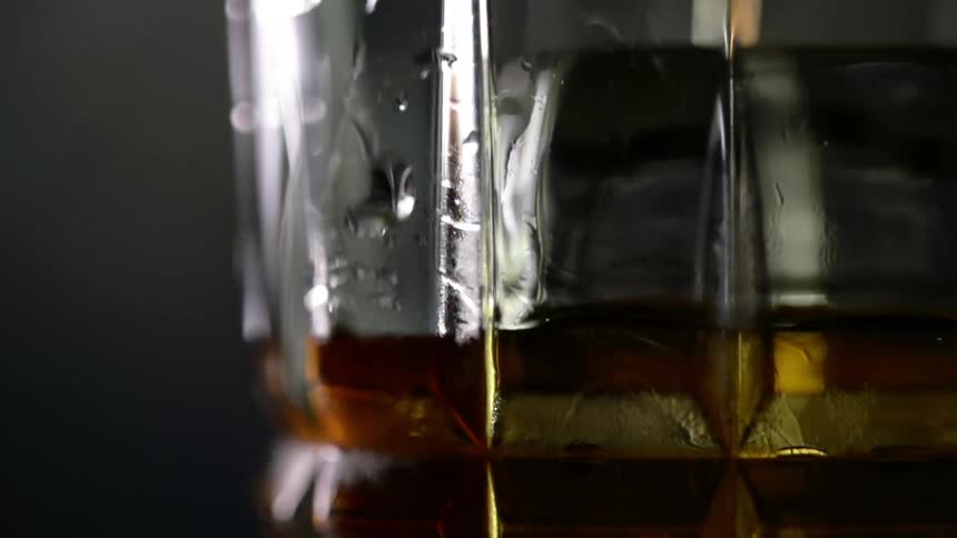 Extreme close up of whiskey pouring inside a glass