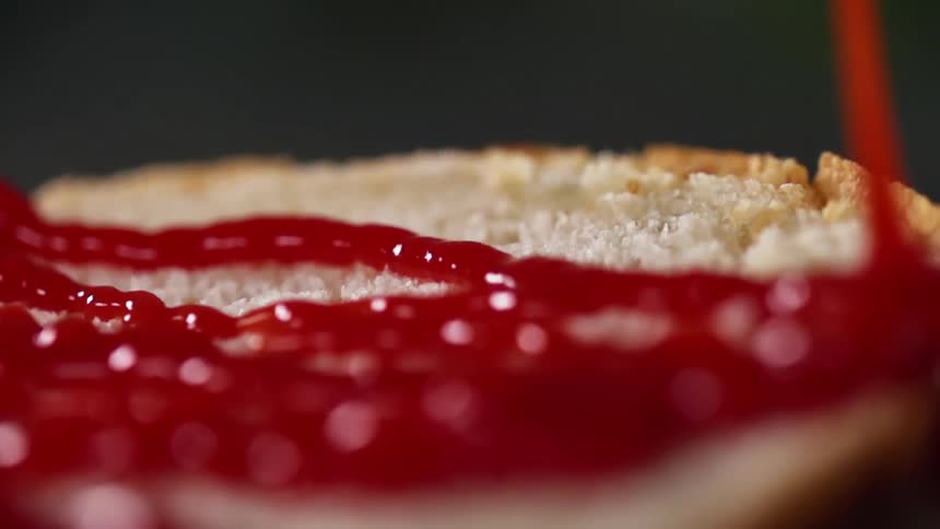 Ketchup  is poured on a bun