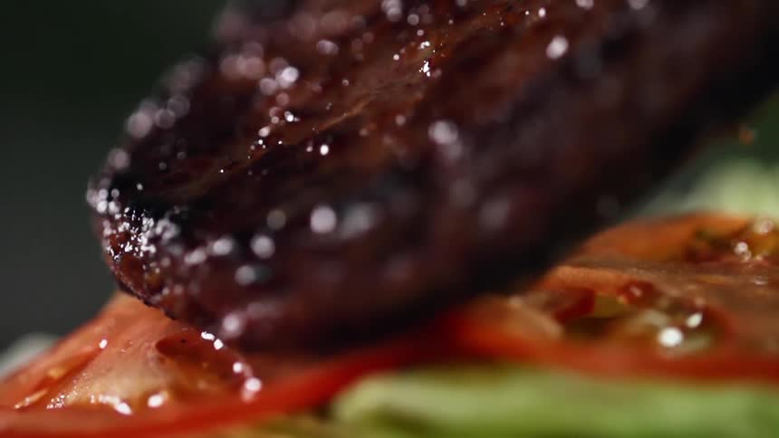A burger patty is placed onto the lettuce and tomato
