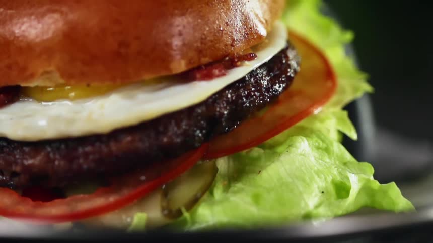A hamburger with bacon and fried egg is being served