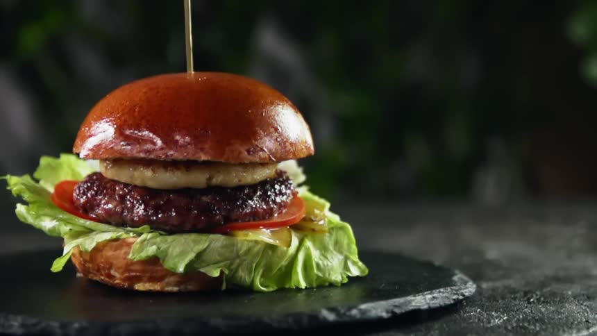 Gourmet hamburger resting on a dark stone slab