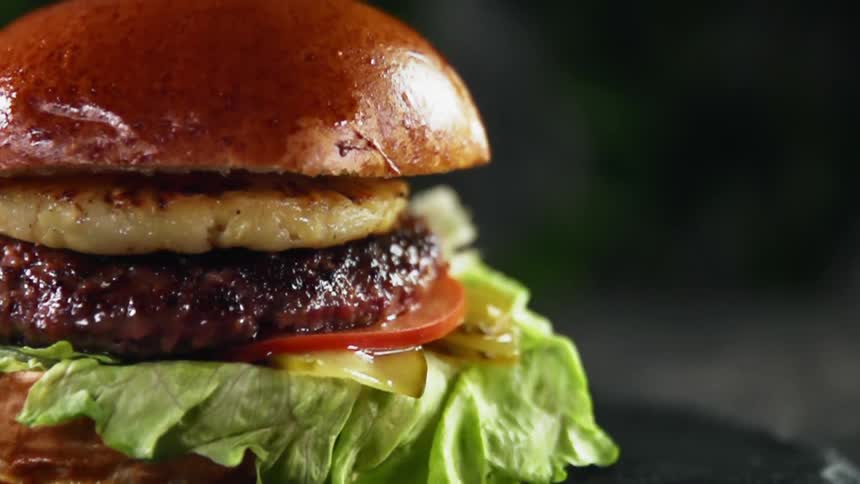 The top half of a hamburger bun falls atop the burger causing the contents to shake