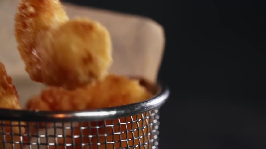 Fried shrimp nuggets being dropped into a basket
