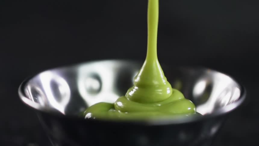 Guacamole being poured into a silver bowl