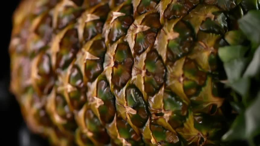 A person places a pineapple used as bowl on top of a stem