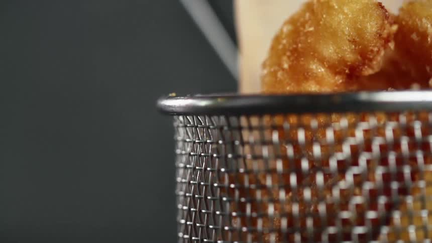 Fried shrimp nugget being dropped into a basket