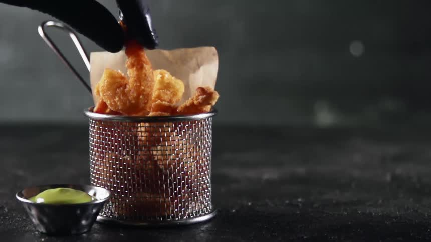 Black gloved hand takes fried shrimp out of basket