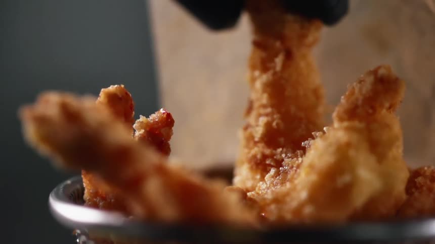 A person picks up a fried shrimp