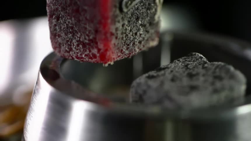 Heated charcoal cubes are dropped into a metal ring