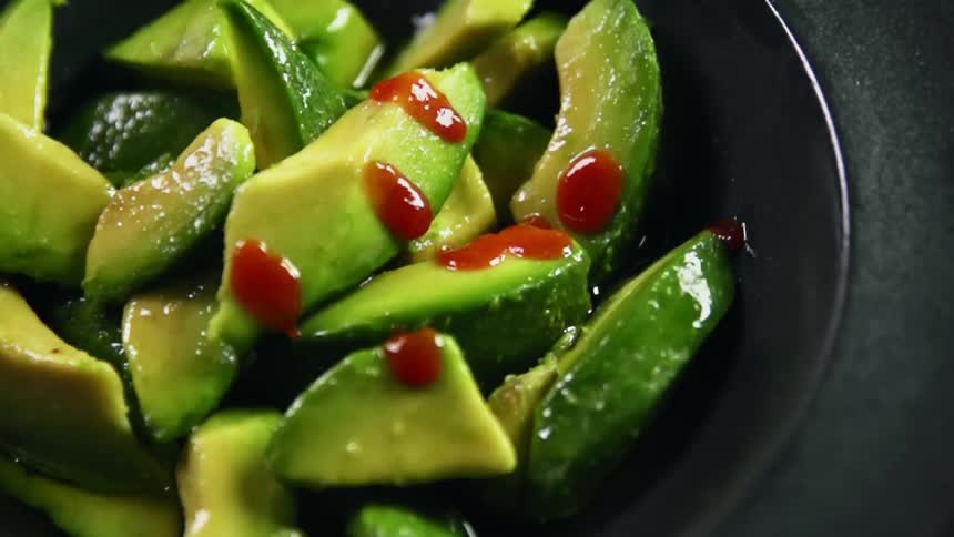 Chili sauce drips onto chunks of avocado