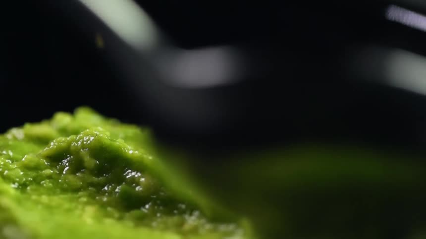 Spoon reflects food and light while stirring guacamole