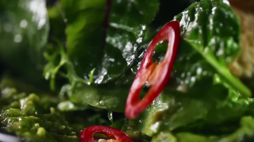 Sliced red chili peppers are added to a spinach salad