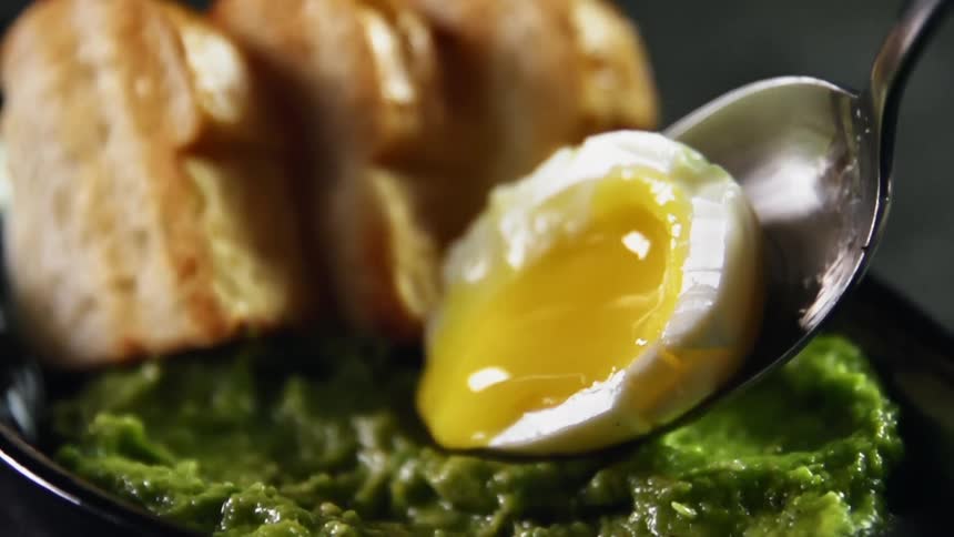 A soft boiled egg being placed on guacamole