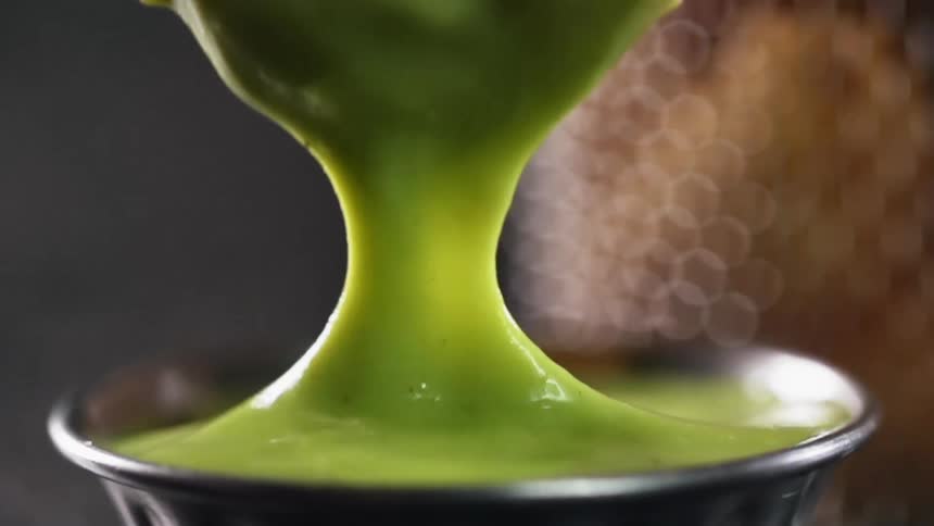 A piece of fried shrimp coated in breadcrumbs is dipped into guacamole