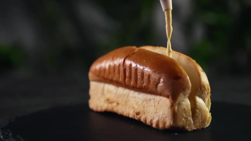 Pouring mustard inside a hot dog bun