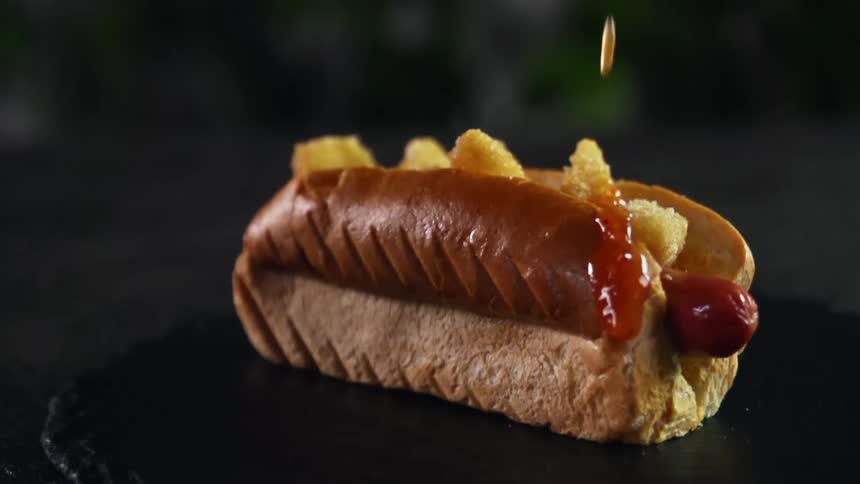 Ketchup falling on a hot dog in a bun