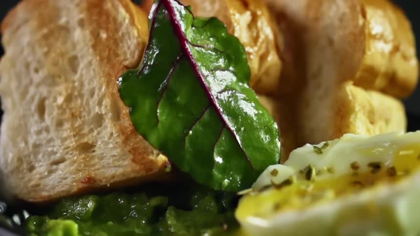 A spinach leaf is dropped down by toasted bread and a soft boiled egg