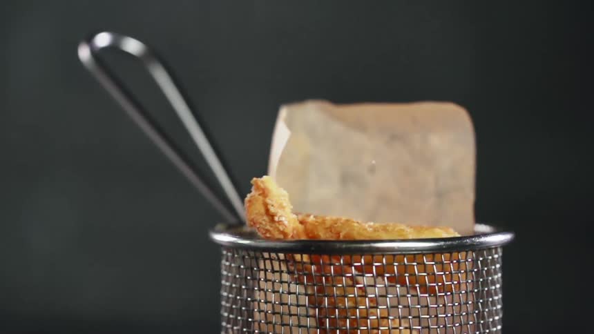 Friend shrimp is dropped into a metal basket
