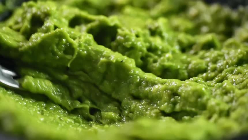 Avocado is mashed with a fork to make guacamole