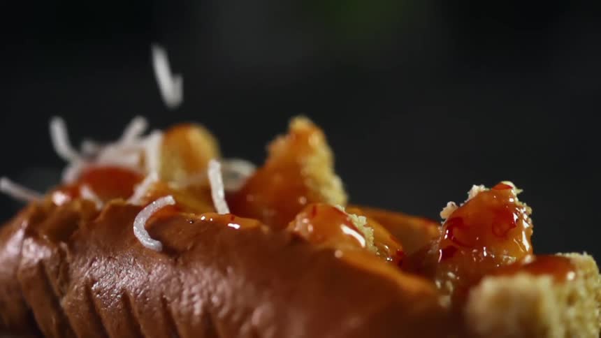 Shredded cheese falling on a hot dog with tiny nuggets