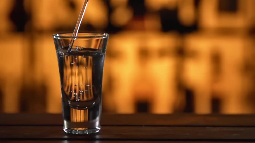 Liquor is poured to the top of a shot glass