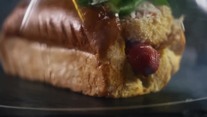 Steam rises from a hot dog on a bun sitting on a plate