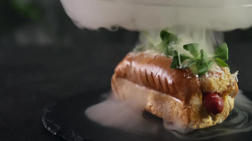 Steam rises from a hot dog on a bun sitting on a plate