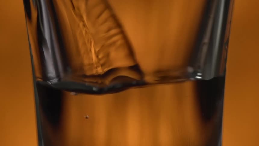 A brown liquid is being poured into a glass