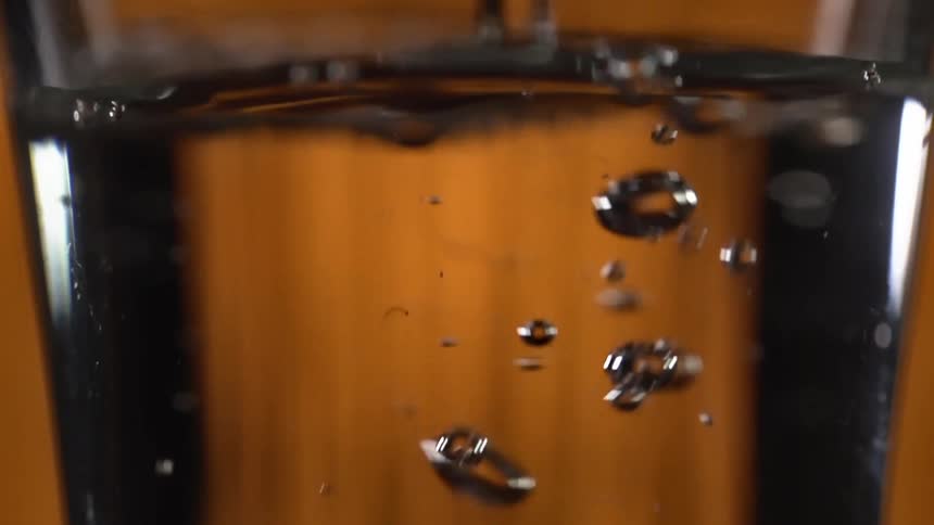 Soda water is being poured into a glass in a bar