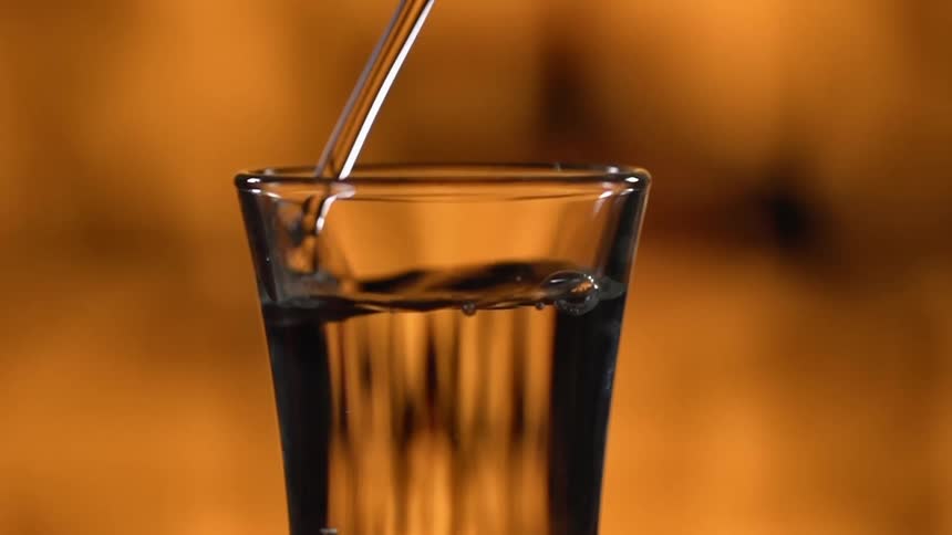 Soda water is being poured into a glass in a bar