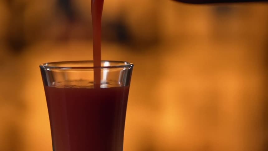 A beverage is poured from a pitcher into a glass