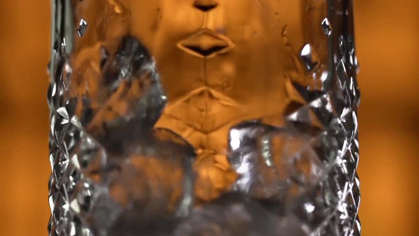 Ice cubes are being dropped into a glass in a bar