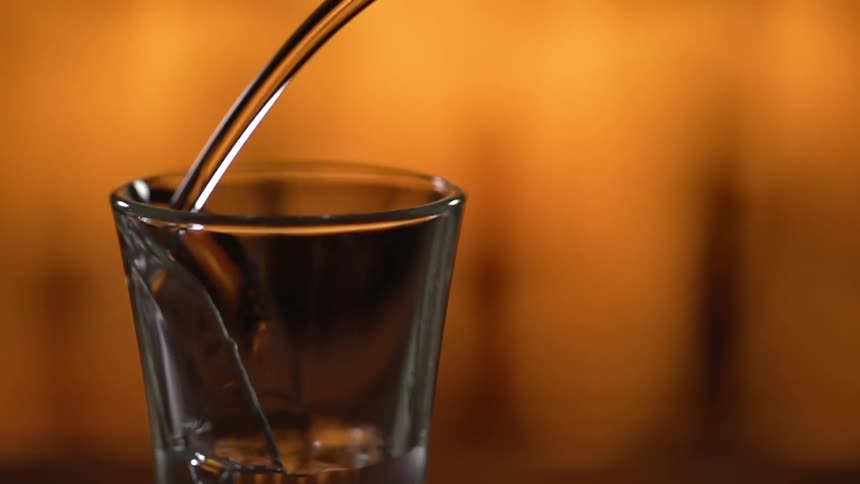 Soda water is being poured into a glass in a bar