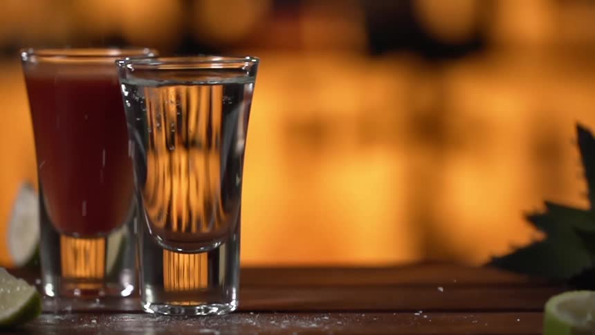 Salt falling on top of shot glasses on a bar top