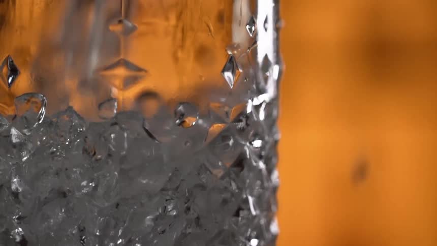 Close up of ice cubes being dropped into a glass in a bar