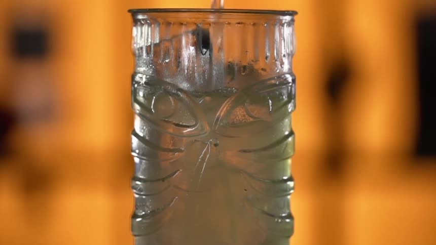 Liquor pouring in a glass filled with ice cubes
