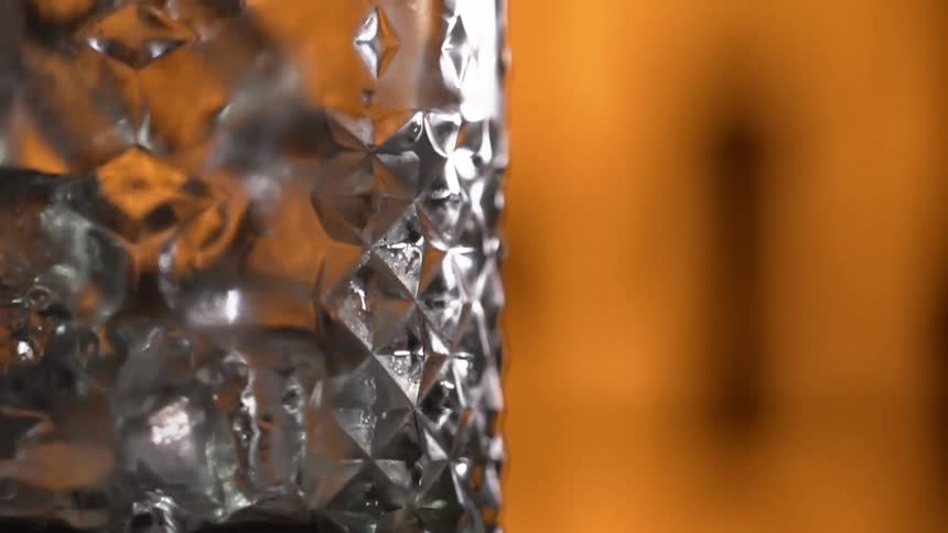 A crystal glass with ice falling in to it