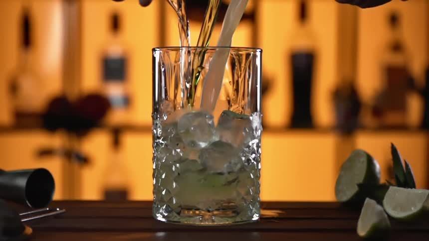 Cocktail being poured over ice at a bar